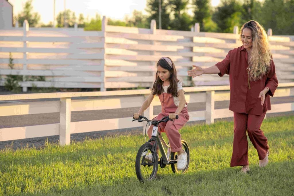 A female walking by her little daughter riding an electric balance bike